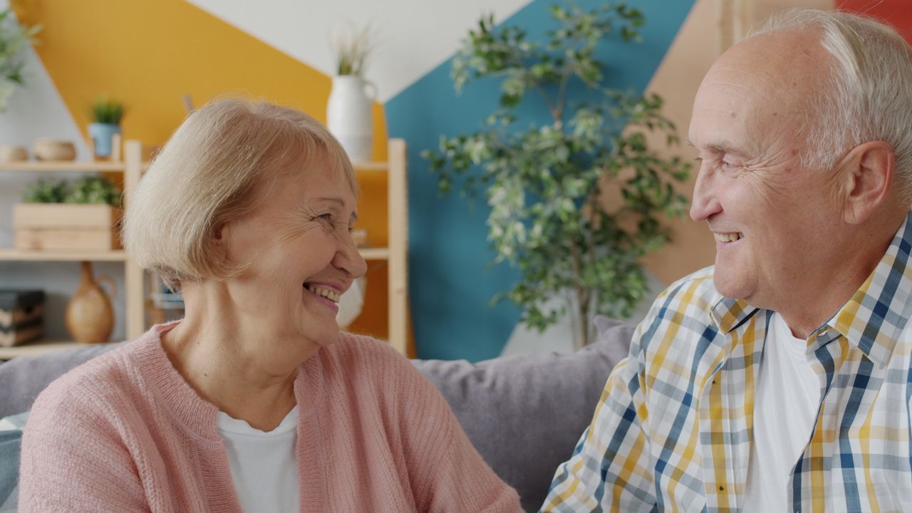 Happy senior couple sharing a joyful moment indoors with a colorful backdrop.