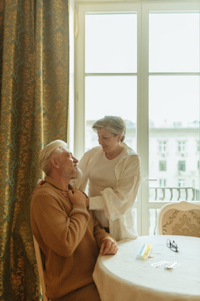 Warm and affectionate scene of an elderly couple sharing a moment at home by a window.